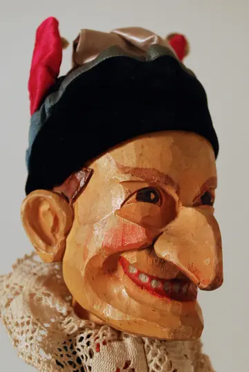 Kasper drei laufen hintereinander: Person in einem Fass, Person, die einer Holzplatte steckt, Person mit Peitsche