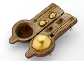 Aräometer mit Flüssigkeit gefülltes Röhrchen mit großer Kugel am Ende, dazu Anhänger, in einer Schatulle