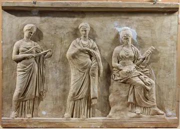Abschnitt von der sog. Musenbasis von Mantineia drei in eine Skulptur gemeißelte Skulpturen nebeneinander stehend, teilweise mit Musikinstrumenten